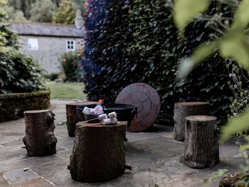 A garden with a fire pit and log seating at Carrholme Cottage Settle