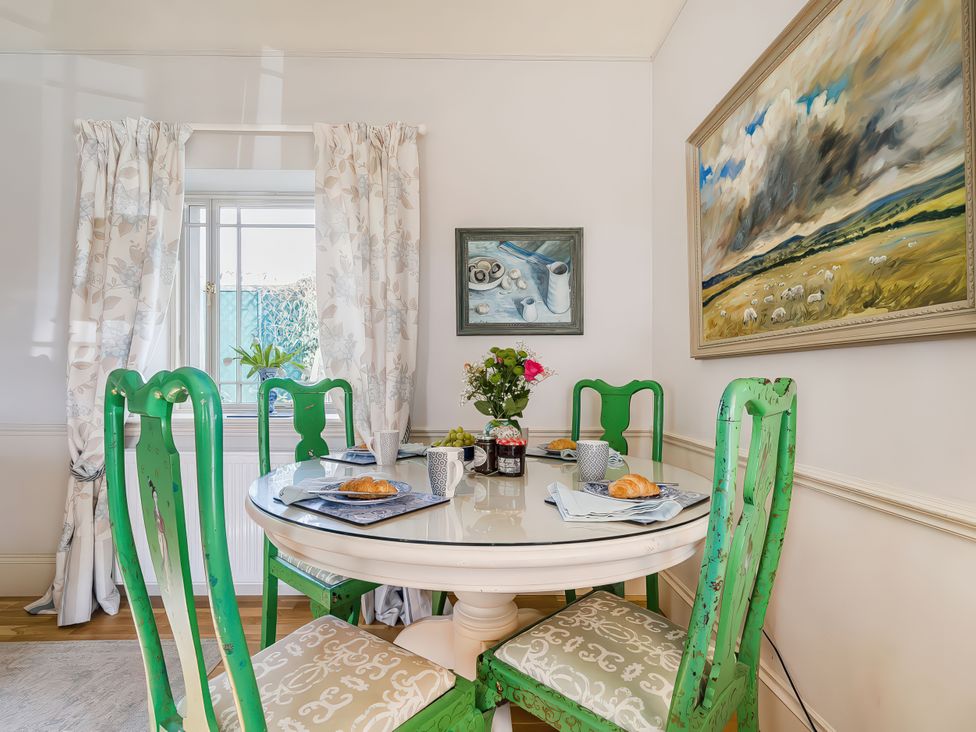 A dining room with a round table and green chairs at Mappowder Cottage Buckland Newton near Dorchester