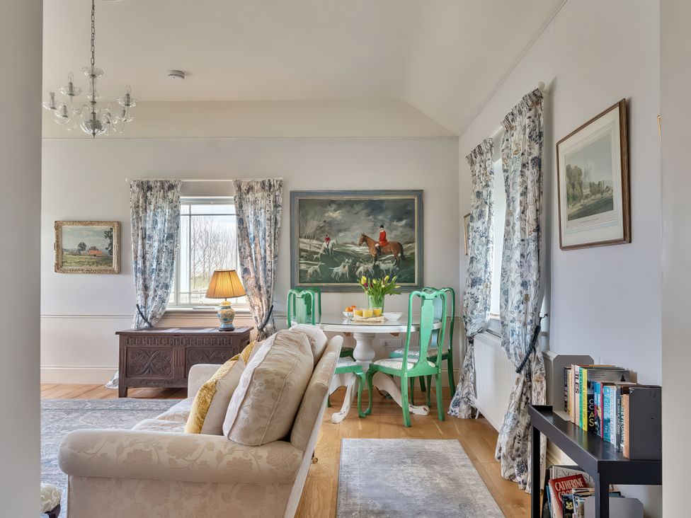 A living room with a table and green chairs at Maple Cottage Buckland Newton near Dorchester