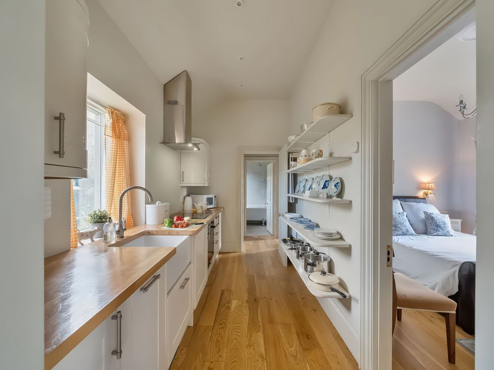 A kitchen with a sink and shelf storage at Maple Cottage in Buckland Newton near Dorchester