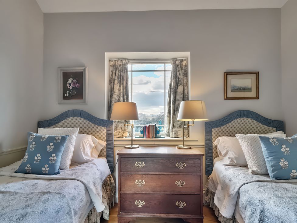 A bedroom with two beds and a window at Maple Cottage in Buckland Newton near Dorchester