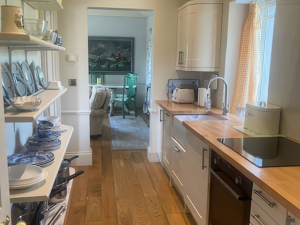 A kitchen with shelves of dishes and a sink at Maple Cottage in Buckland Newton near Dorchester