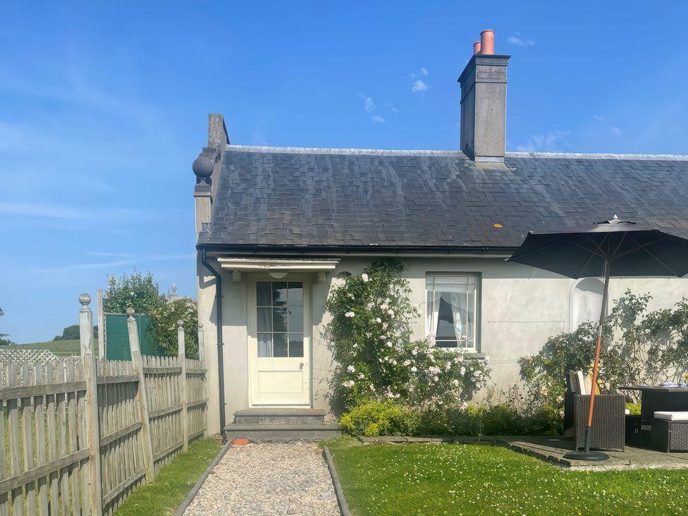 A house with a door and window surrounded by a garden at Maple Cottage in Buckland Newton near Dorchester