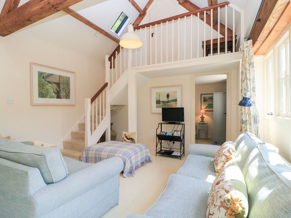A living room with a sofa and television at Upper Mill Barn, Coln St Aldwyns, near Bibury