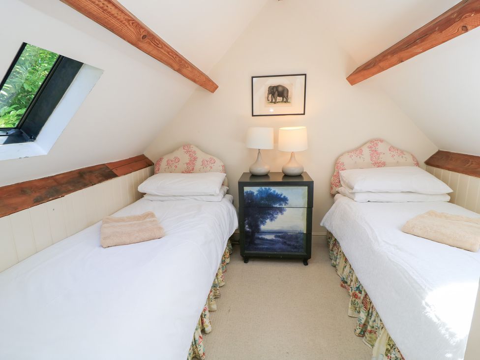 A bedroom with two single beds and a black bedside table at Upper Mill Barn, Coln St Aldwyns, near Bibury