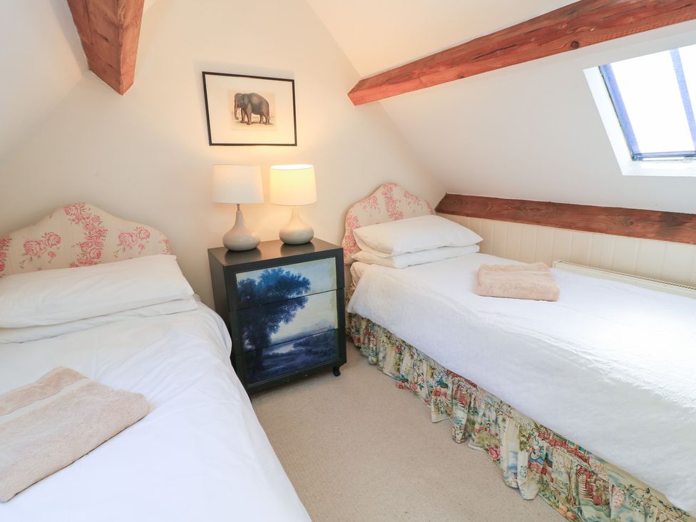 A bedroom with two beds and a nightstand at Upper Mill Barn, Coln St Aldwyns, near Bibury