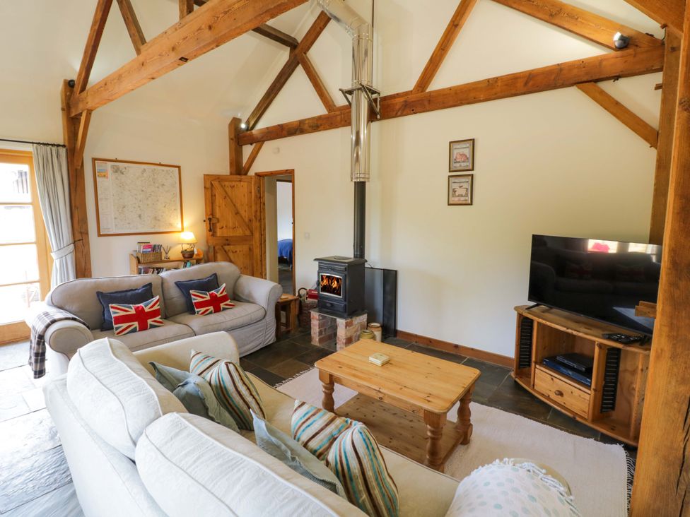 A living room with a wood stove and sofa at Robbie's Barn Fulready near Stratford-upon-Avon