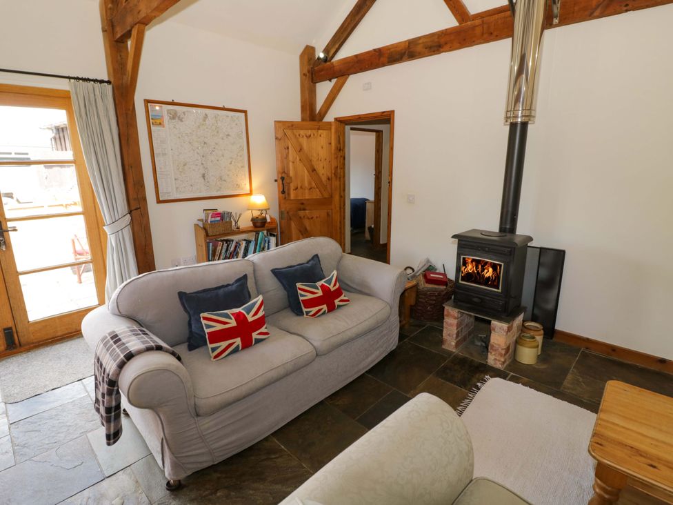 A living room with a wood stove and sofa at Robbie's Barn Fulready near Stratford-upon-Avon