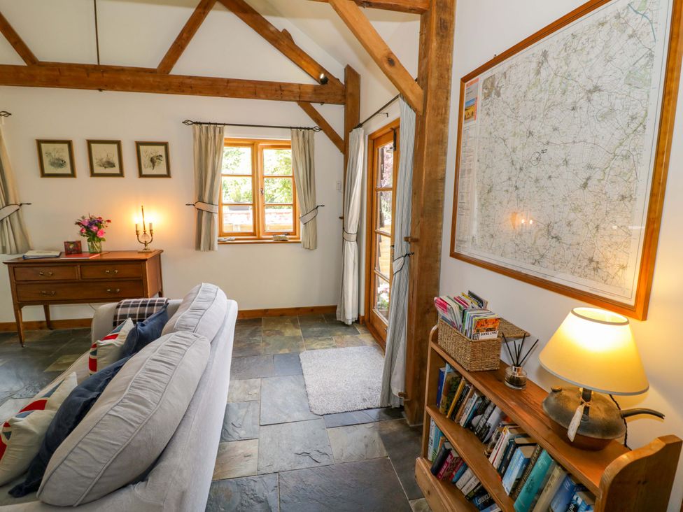 A living room with a sofa and bookshelf at Robbie's Barn Fulready near Stratford-upon-Avon