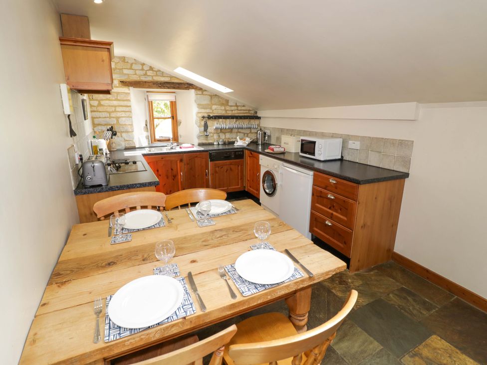 A kitchen with a dining table and appliances at Robbie's Barn Fulready near Stratford-upon-Avon