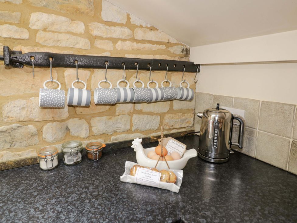 A kitchen with mugs hanging, a kettle, jars, eggs, and a plate of cookies at Robbie's Barn Fulready near Stratford-upon-Avon