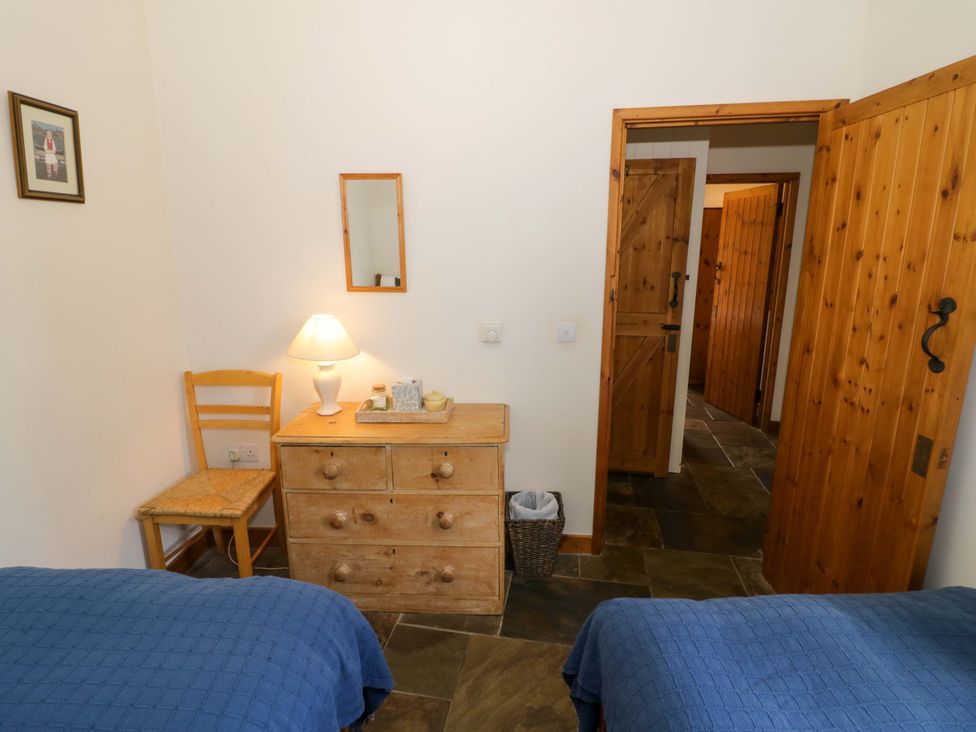 A bedroom with two beds, a dresser, and a chair at Robbie's Barn Fulready near Stratford-upon-Avon