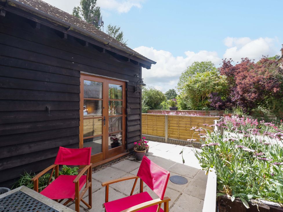An outdoor seating area with red chairs by double doors at Robbie's Barn Fulready near Stratford-upon-Avon