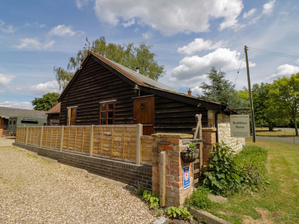 A holiday cottage with wooden fence and sign at Robbie's Barn in Fulready near Stratford-upon-Avon