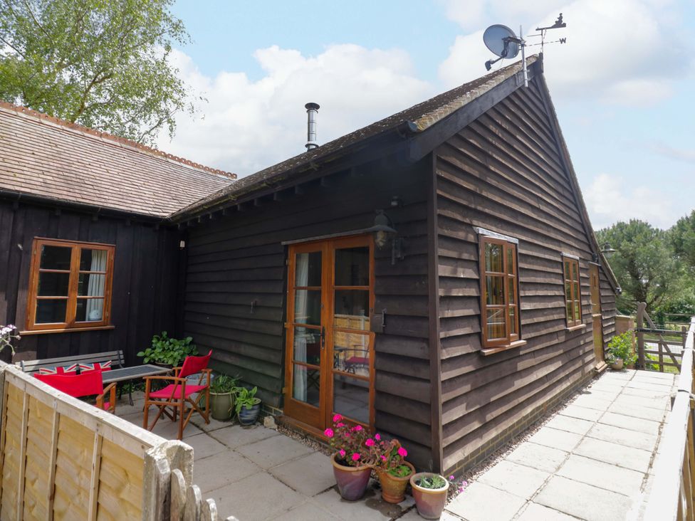 An outdoor view of a wooden building with a patio at Robbie's Barn Fulready near Stratford-upon-Avon