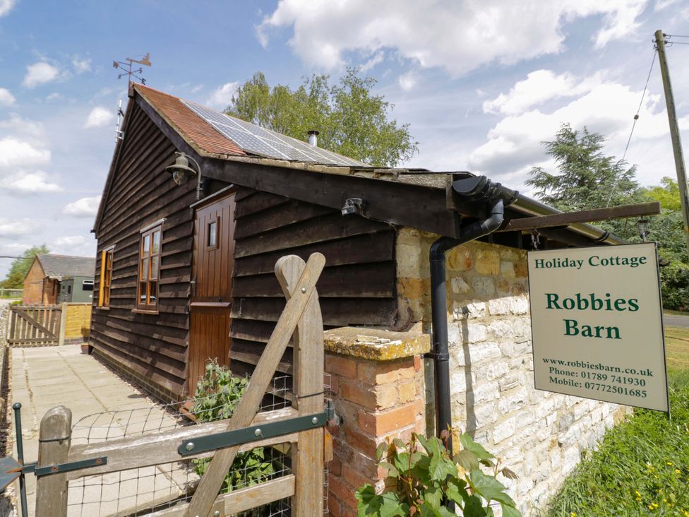 Exterior view of a holiday cottage with a sign at Robbie's Barn Fulready near Stratford-upon-Avon