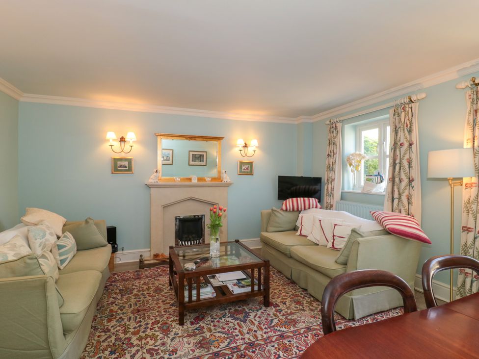 A living room with two sofas a coffee table a fireplace and a window at Batemans Nailsworth