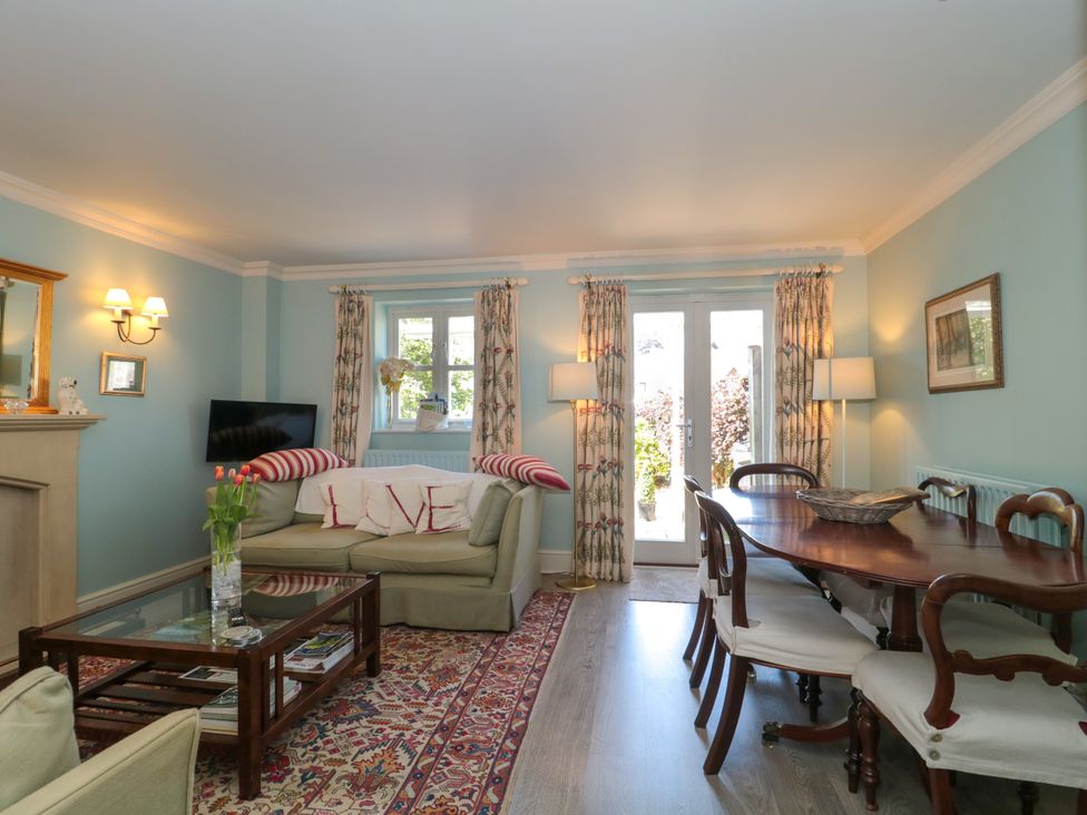 A living room with a sofa dining table and chairs and French doors at Batemans Nailsworth