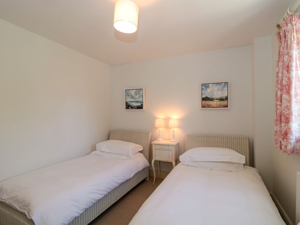 A bedroom with two single beds a nightstand with two lamps and paintings on the wall at Batemans in Nailsworth