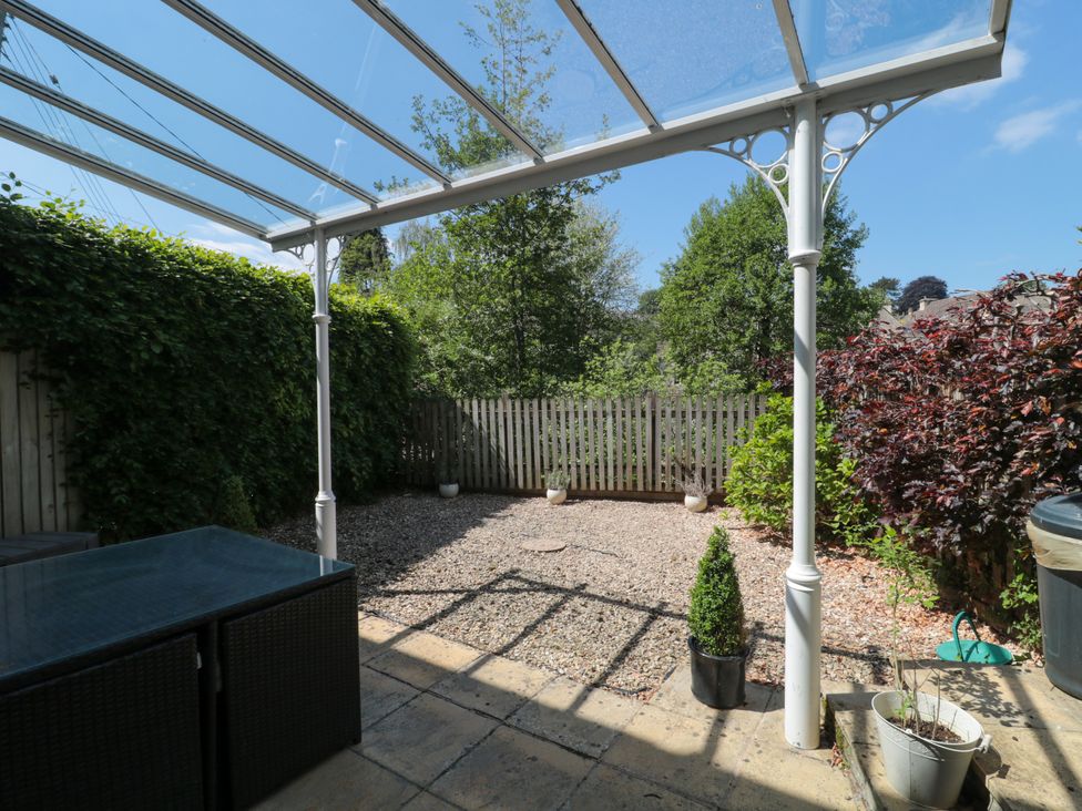 An outdoor patio area with a glass roof and plants along a wooden fence at Batemans Nailsworth