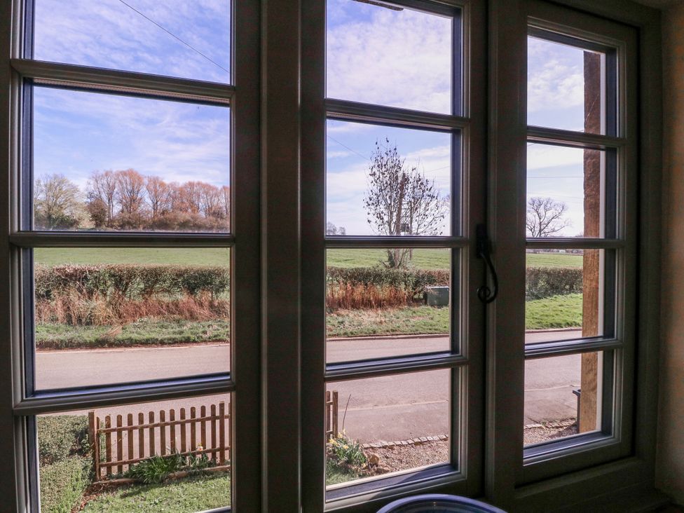 A view from a window showing trees, a field, and a road at Elm View Chipping Campden