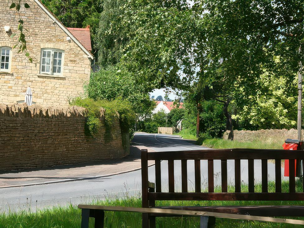 A view of a road with a bench and a stone wall at Elm View in Chipping Campden