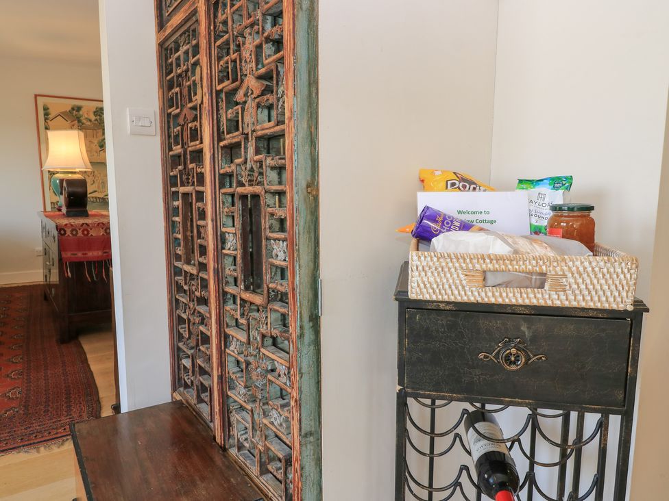 A hallway with a decorative door and a basket of snacks at Fairview Cottage in Milton-Under-Wychwood