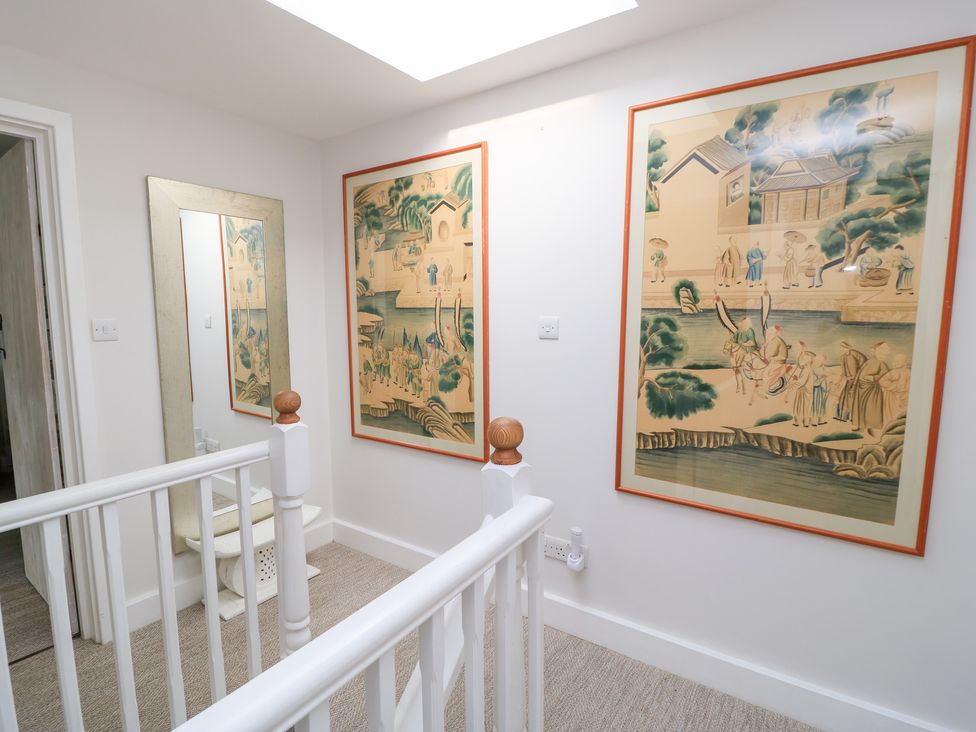 A hallway with wall art and a mirror at Fairview Cottage in Milton-Under-Wychwood