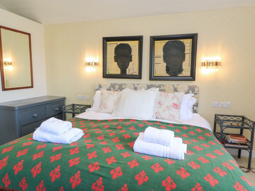 A bedroom with a bed and artwork on the walls at Fairview Cottage in Milton-Under-Wychwood