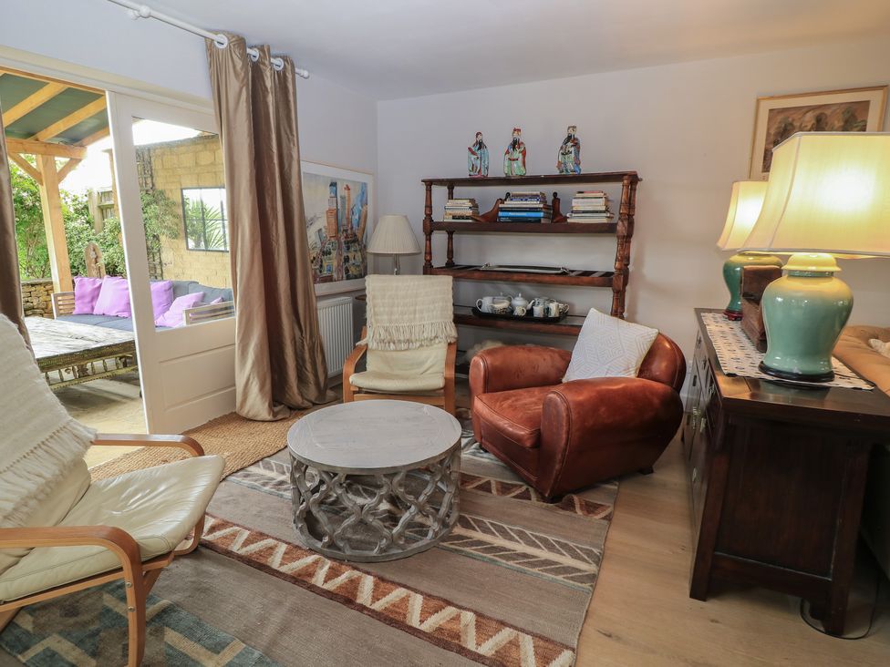 A living room with a bookshelf and coffee table at Fairview Cottage in Milton-Under-Wychwood