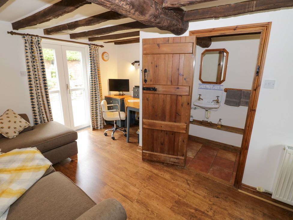 A living room with a desk and sink at Elmhurst Cottage in Lower Quinton