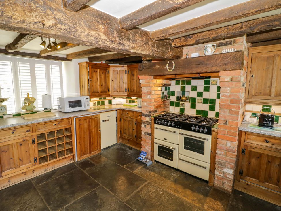 A kitchen with cabinets, stove, and microwave at Elmhurst Cottage in Lower Quinton