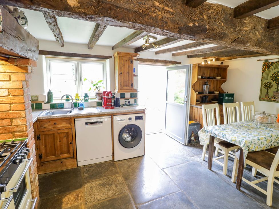 A kitchen with a sink, dishwasher, and table at Elmhurst Cottage in Lower Quinton