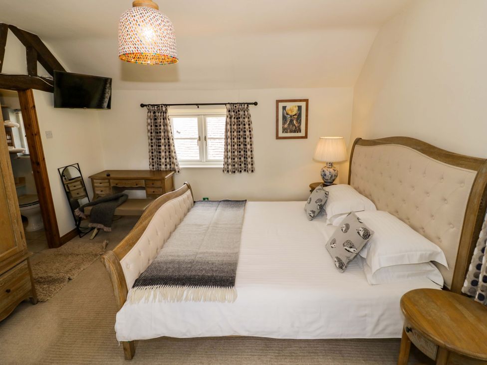 A bedroom with a bed and a desk at Elmhurst Cottage in Lower Quinton