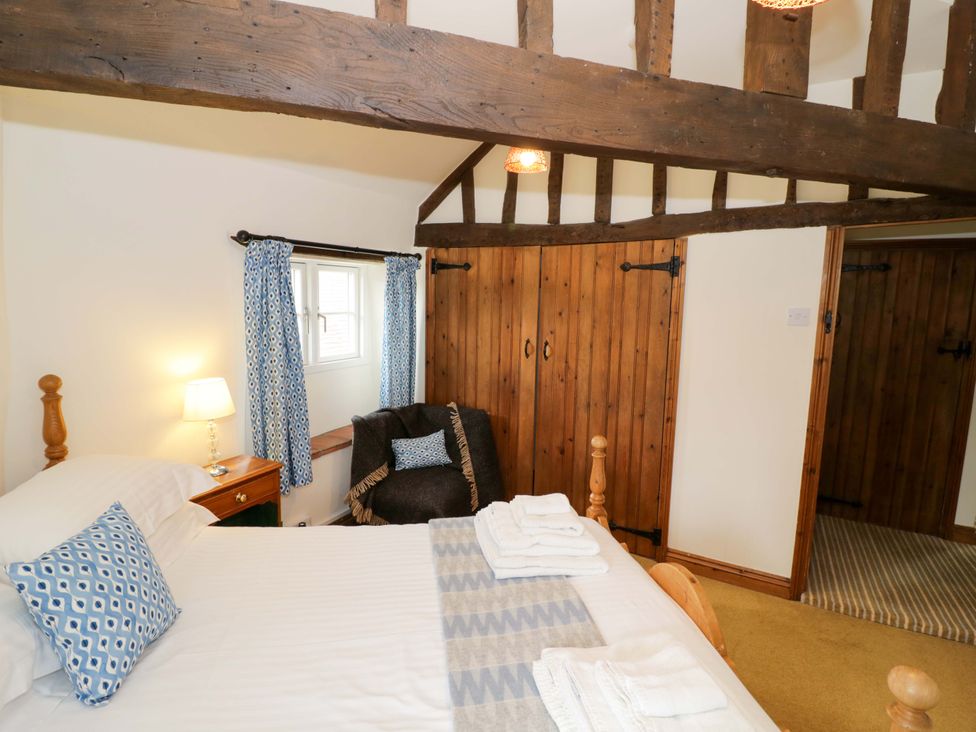 A bedroom with a bed and wooden features at Elmhurst Cottage in Lower Quinton