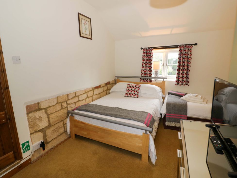 A bedroom with a bed and television at Elmhurst Cottage in Lower Quinton