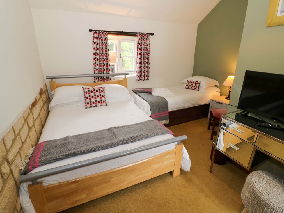 A bedroom with two beds and a television at Elmhurst Cottage in Lower Quinton