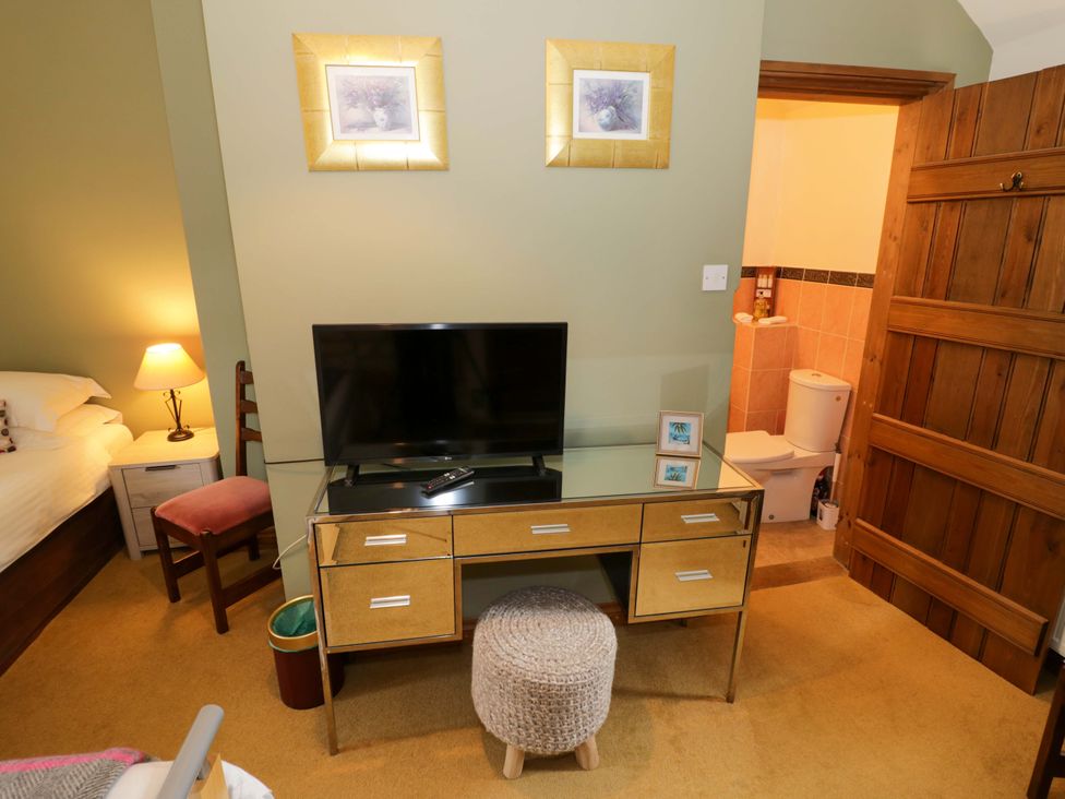 A bedroom with a television and a chair at Elmhurst Cottage in Lower Quinton