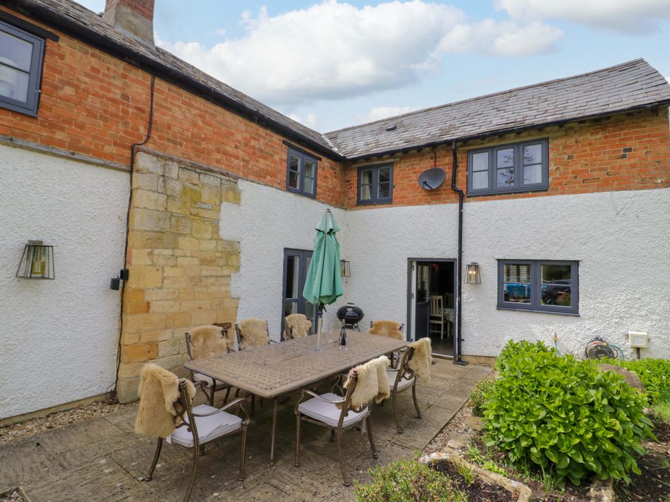 An outdoor dining area with a table and chairs at Elmhurst Cottage in Lower Quinton