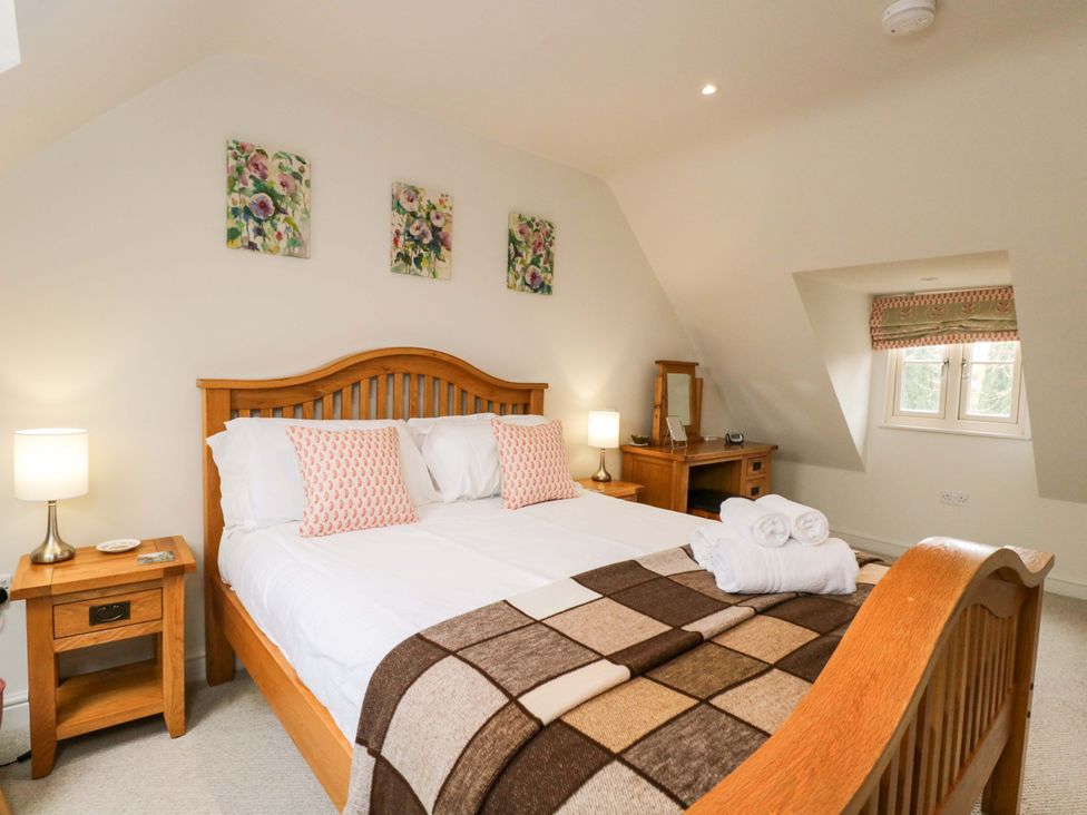 A bedroom with a wooden bed and decorations at Church View in Bourton-On-The-Water