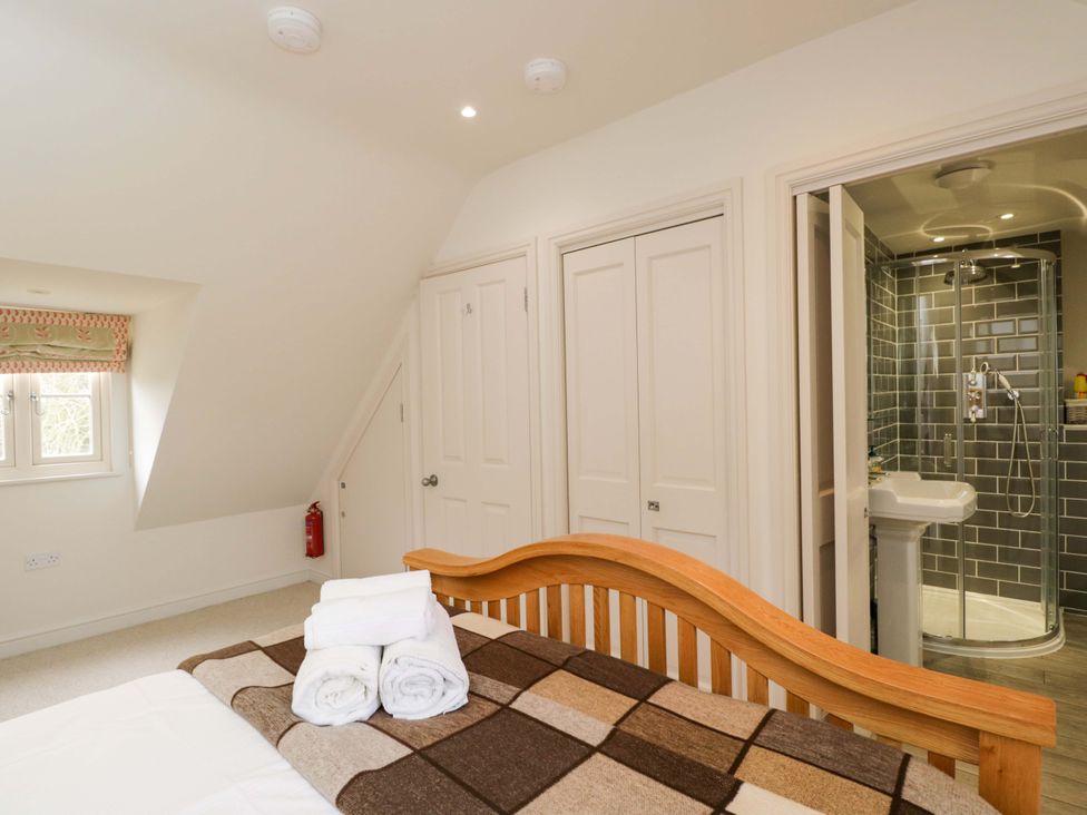 A bedroom featuring a bed with towels and an attached shower at Church View in Bourton-On-The-Water