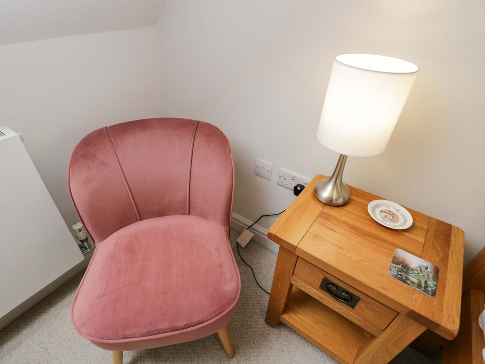 A living room with a pink chair and a lamp at Church View in Bourton-On-The-Water