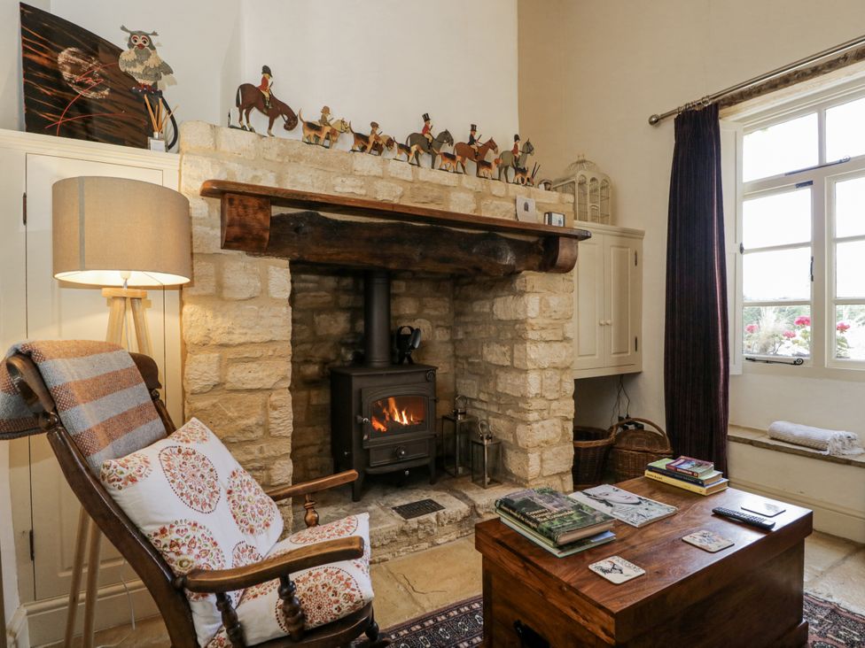 A living room with a fireplace and armchair at The Old Reading Room in Bledington near Stow-on-the-Wold