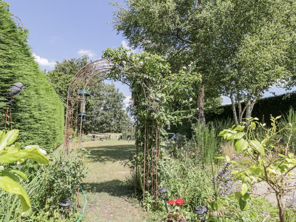 A garden with an archway and plants at The Old Reading Room Bledington near Stow-on-the-Wold