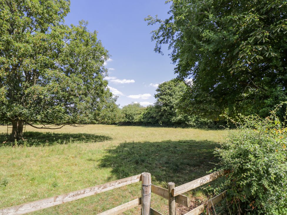 A field with trees and a wooden fence at The Old Reading Room Bledington near Stow-on-the-Wold