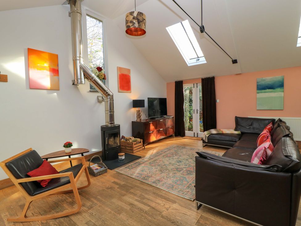 A living room with a sofa, coffee table, and television at The Linhay in Little Coxwell near Faringdon