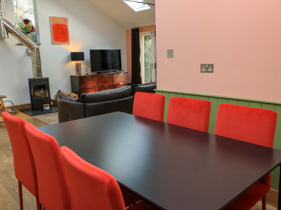 A dining room with a table and chairs next to a living area with a television at The Linhay Little Coxwell near Faringdon