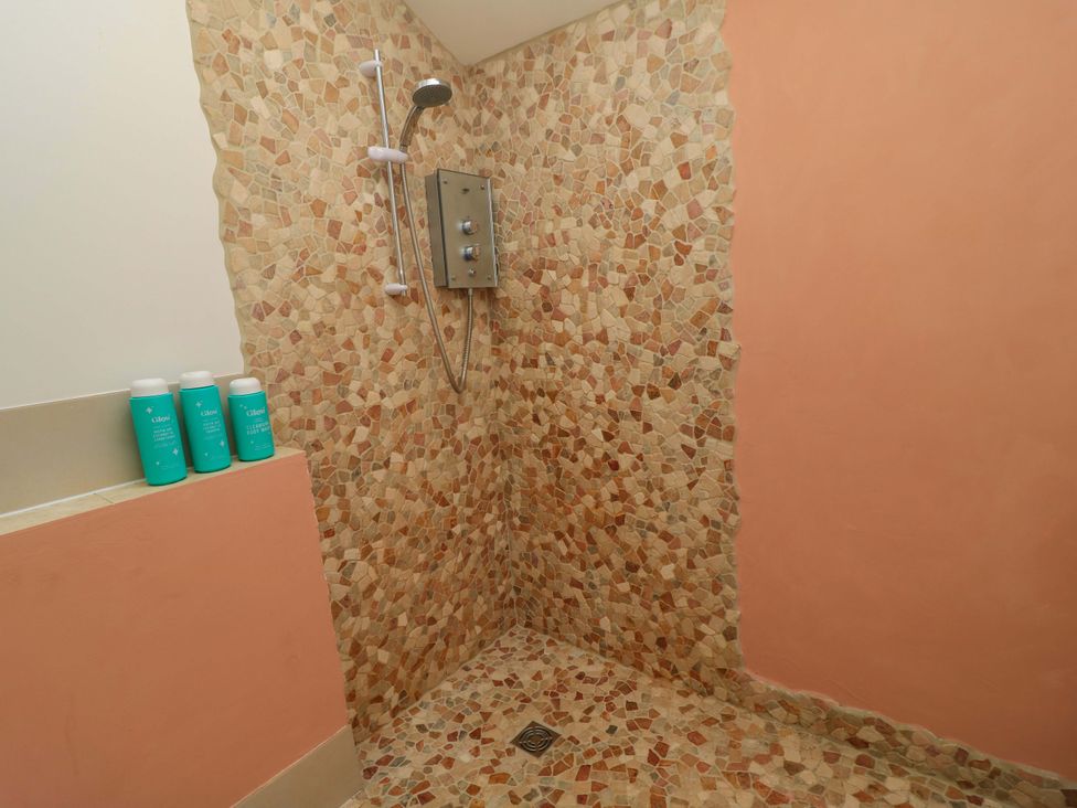 A shower area with stone walls and shampoo bottles at The Linhay in Little Coxwell near Faringdon