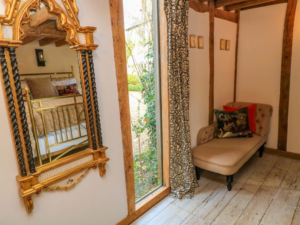 A bedroom with a mirror and a chair at The Linhay Little Coxwell near Faringdon