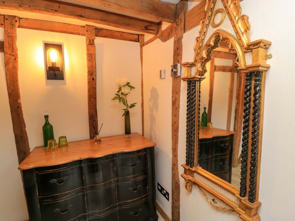 A hallway with a dressing table, mirror, and flower vase at The Linhay Little Coxwell near Faringdon